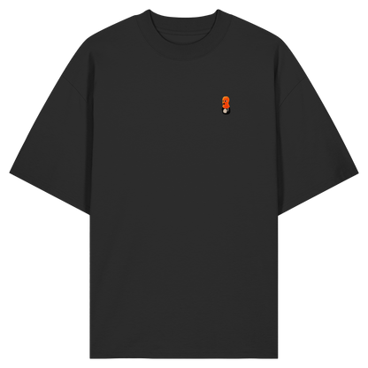 Die Vorderansicht eines schwarzen Oversized-T-Shirts mit Rundhalsausschnitt und weiten Ärmeln. Auf der linken Brust befindet sich ein kleiner, minimalistischer Print eines Pinguin-Charakters mit einem markanten orange-roten Kopf-Element beziehungsweise einer orangefarbenen Haube. Das Produktbild ist vor einem transparenten, karierten Hintergrund freigestellt